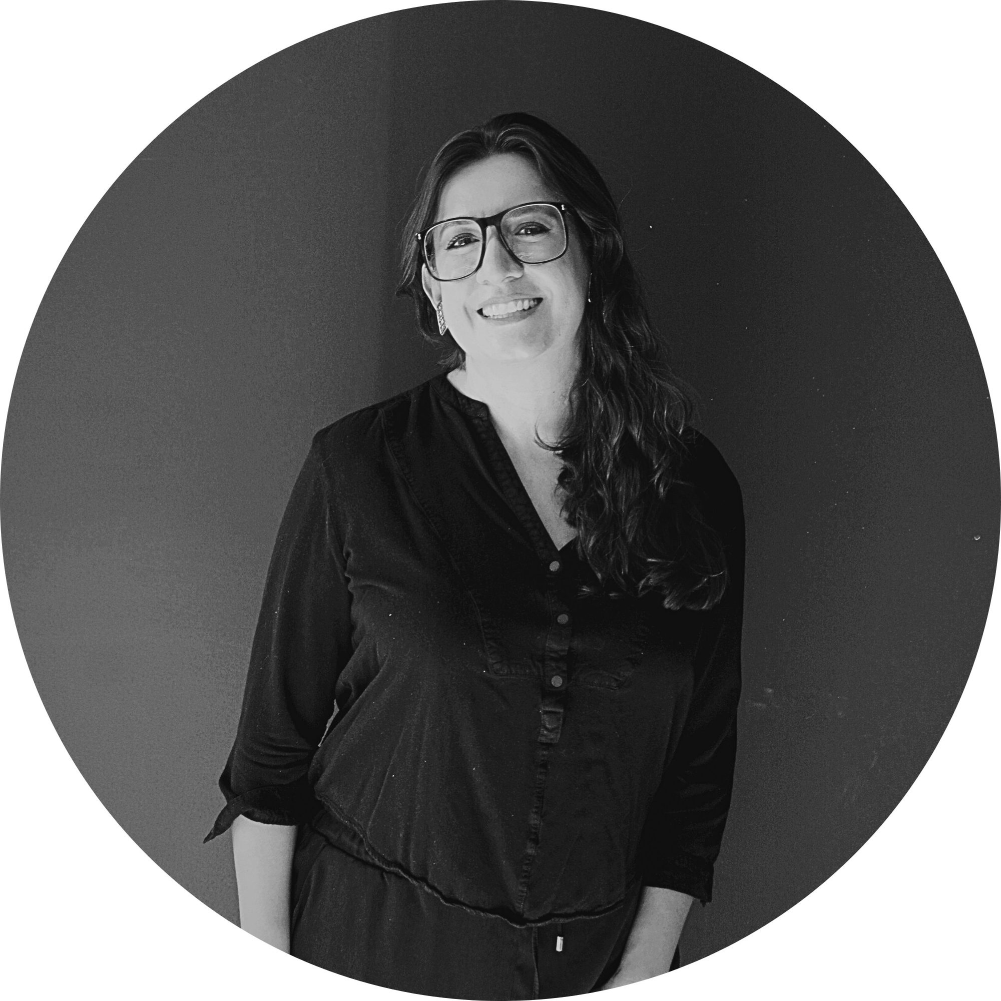 Fotografía en blanco y negro de la filósofa mexicana Itzamá Enríquez Íñiguez. Ella es una mujer de mediana. En la foto está sonriendo. Lleva gafas de montura gruesa y su cabello, que es onduldado, le cae sobre los hombros. El fondo del retrato es una liso y oscuro.