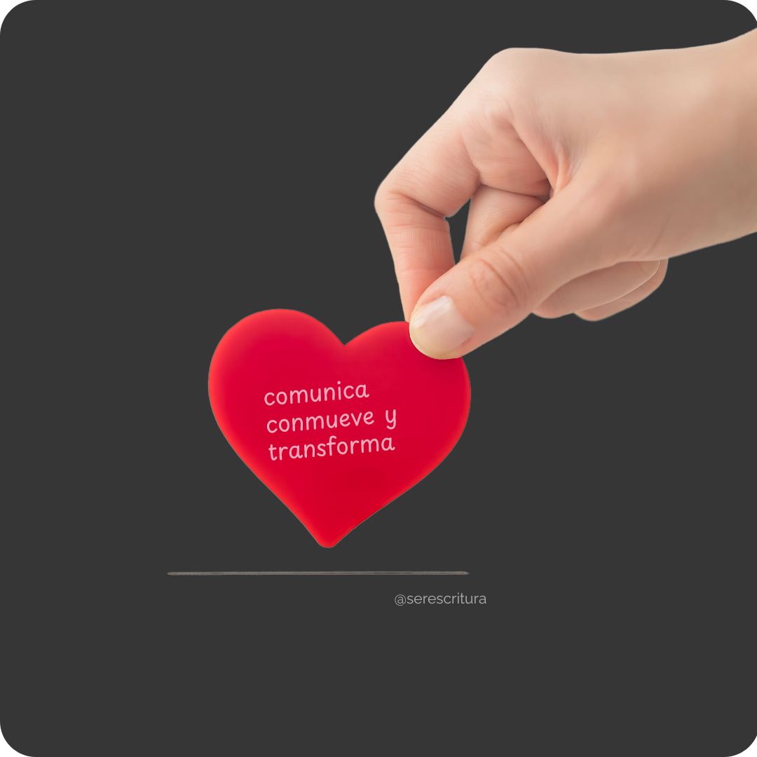 Una mano está colocando o sosteniendo suavemente un corazón de color rojo brillante sobre un fondo gris oscuro. En el centro del corazón rojo, se leen tres palabras en blanco: "comunica, conmueve y transforma". Debajo del corazón, hay una línea horizontal y la cuenta de '@serescritura' en blanco. La imagen acompaña el curso de redacción profesional: "Informes que inspiran: comunica, conmueve y transforma".