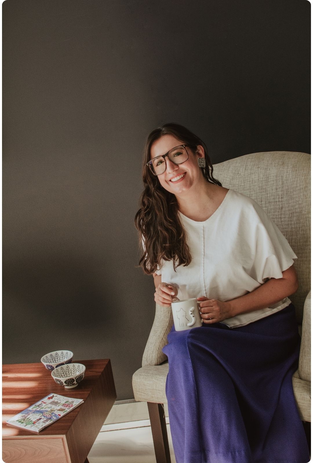 Itzamá Enríquez Íñiguez, fundadora y consultora editorial de Ser Escritura, es de cara larga, nariz grande, ojos medianos, boca chica, labios delgados, complexión media, piel morena y cabello castaño, de largo medio. Lleva gafas grandes color café, blusa blanca y falda larga azul. Sus aretes son de plata con motivos prehispánicos. Itza (como también la llaman) está sentada sobre un sillón de tela beige. En las manos sostiene una taza blanca, con un relieve en forma de cola de gato.
