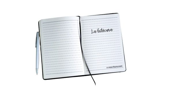 Cuaderno abierto con líneas azules, acompañado de una pluma plateada. En la página derecha se lee “La bitácora” en letra manuscrita, y en la parte inferior está la dirección serescritura.com.