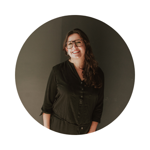 Fotografía de Itzamá Enríquez Íñiguez, tallerista y profesora de redacción. Ella es una mujer de mediana. En la foto está sonriendo. Lleva gafas de montura gruesa y su cabello, que es onduldado, le cae sobre los hombros. El fondo del retrato es liso y oscuro.